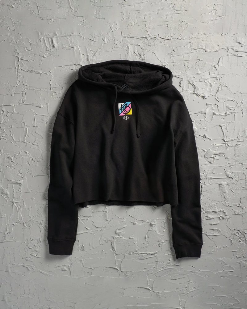 A stylish black cropped hoodie featuring a colorful graphic design on the chest against a textured white background