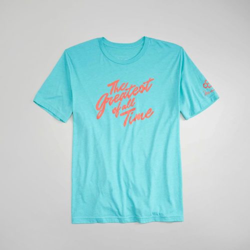 A light blue t-shirt featuring the phrase The Greatest of All Time in bold coral lettering designed for casual wear