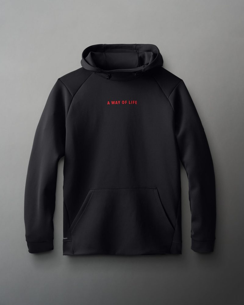 A black hooded sweatshirt with a smooth texture displays 'A WAY OF LIFE' in bold red lettering on the chest, featuring long sleeves and a front kangaroo pocket, set against a soft gray background.