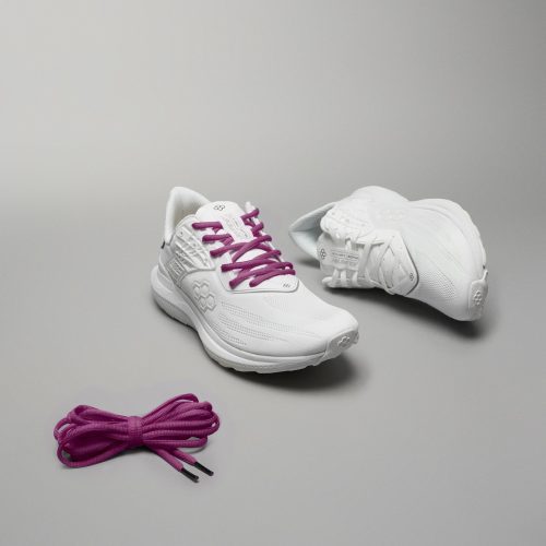 A pair of stylish white athletic shoes with purple laces alongside an extra set of purple shoelaces set against a neutral gray background