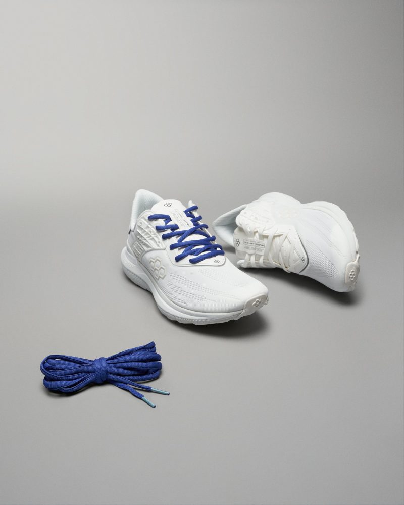 A pair of modern white athletic shoes with blue laces accompanied by a matching set of blue shoelaces displayed against a neutral gray background