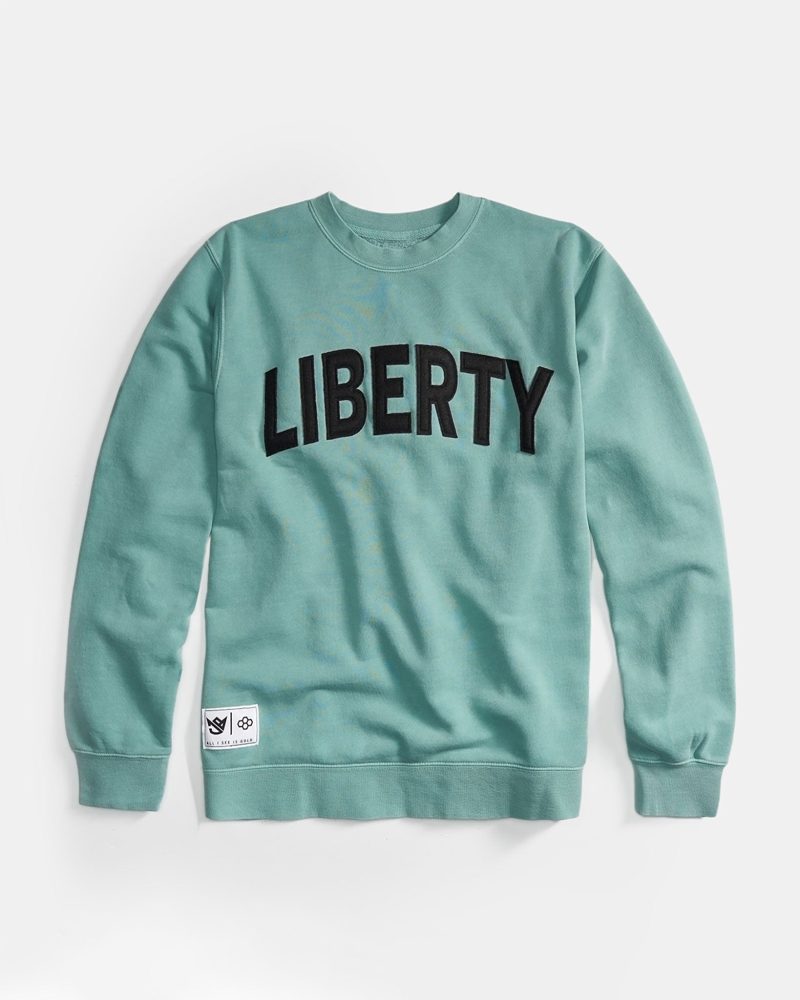 A mint green sweatshirt displaying the word LIBERTY in bold black letters across the chest with a small logo patch at the hem